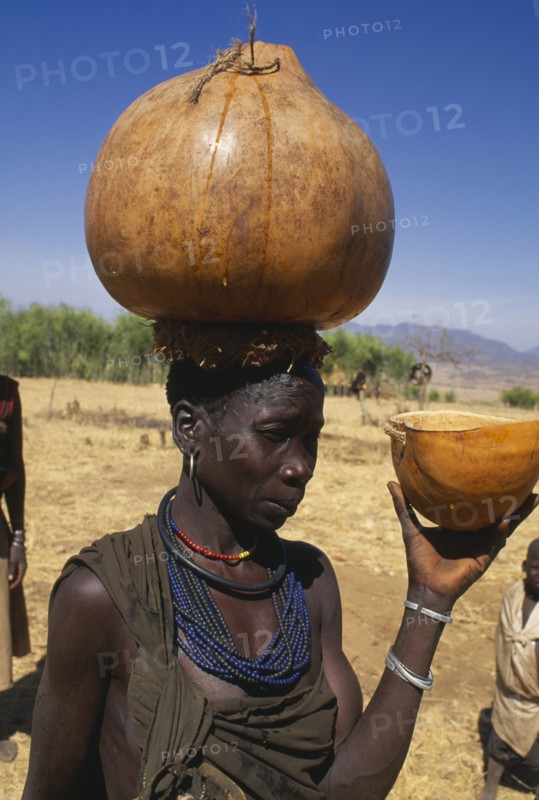 UGANDA, Karamoja, Moroto District, Karamojong woman carrying water gourd on her head.