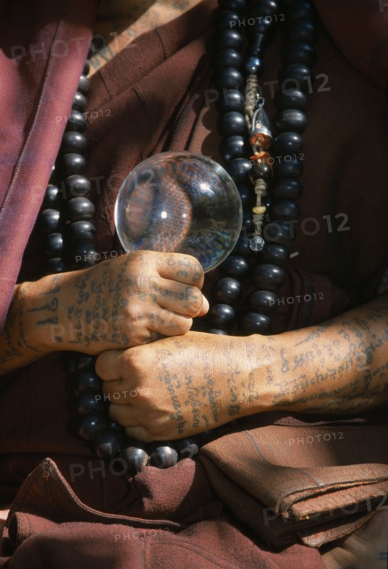 THAILAND, Wat Phra Acha Tong, Cropped vew of Buddhist monk from The Golden Horse Forest Monastery showing tattooed arms and hands and prayer beads.