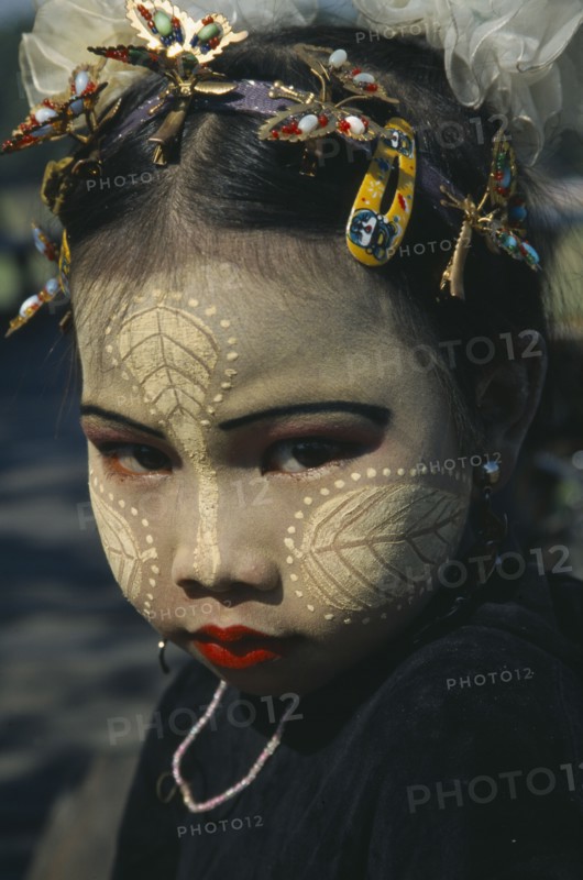 MYANMAR, Lake Taungthaman , Portrait of young girl with face decorated with leaf patterns  and makeup.