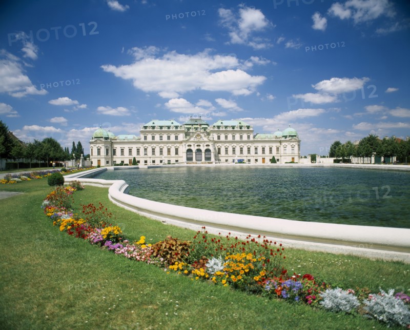 AUSTRIA, Vienna, Belvedere Castle exterior and ornamental lake with colourful flower border in the foreground.
