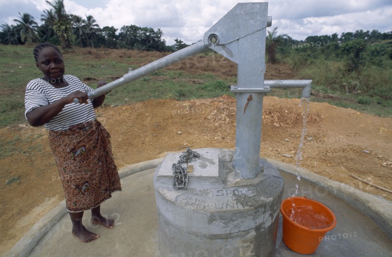 LIBERIA   , Margibi, Kakata, Young woman pumping clean water from UNHCR supplied water pump.