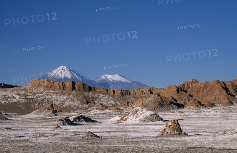 CHILE, Antofagasta, General, Salt deposits on desert surface near San Pedro de Atacama with snow capped peak of Volcano Lincancabur beyond.