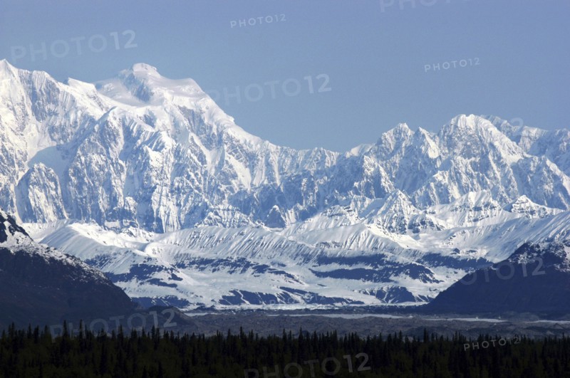 USA, Alaska, Snow covered mountain range seen over green treetops