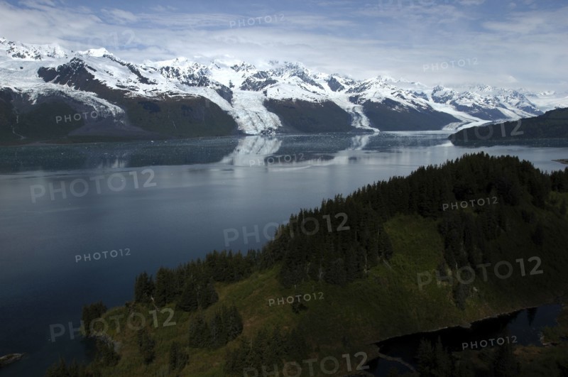 USA, Alaska, College Fjord, View over trees and calm waters of the bay toward snow capped mountain range