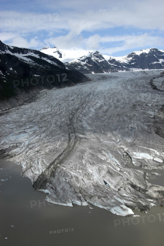 USA, Alaska, Juneau, View over murky waters and valley leading toward snowcapped mountain peaks