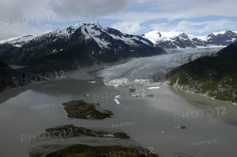USA, Alaska, Juneau, View over murky waters and valley leading toward snowcapped mountain peaks