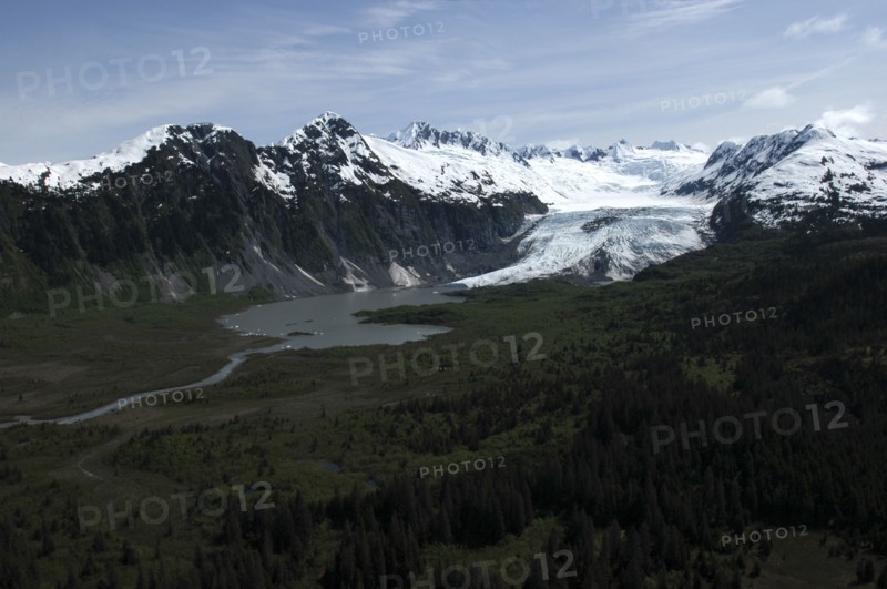 USA, Alaska, Prince William Sound, View over tree covered landscape toward waters and snow capped mountain peaks