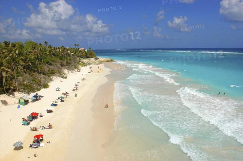 WEST INDIES, Barbados, St Philip, View along Crane beach with scattering of umbrellas and sunbathers