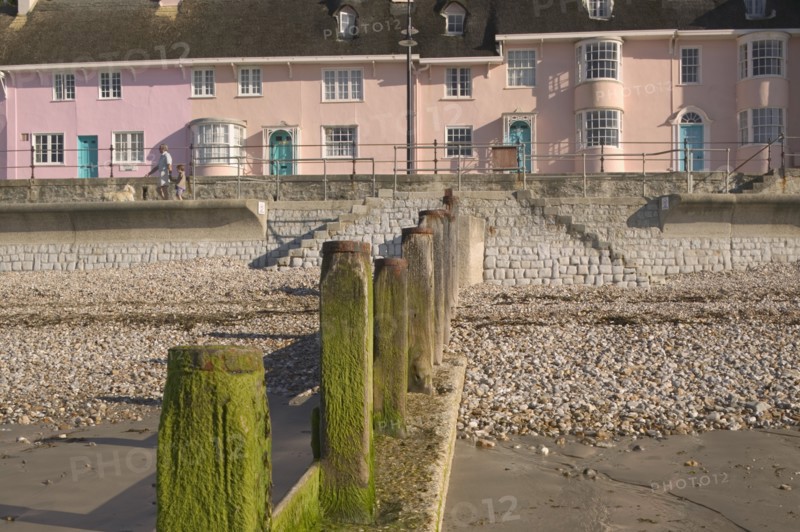 ENGLAND, Dorset, Lyme Regis, View of old fishermens cottages along the waterfront from the beach with a groyne in the foreground.