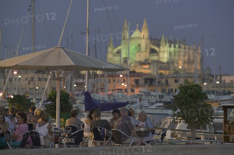 SPAIN, Balearic Islands, Majorca , Waterfront cafe at dusk in Palma de Mallorca with La Seo Cathedral in the background.