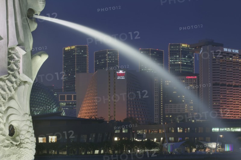 SINGAPORE, Merlion Park, Detail of the Merlion statue at dusk with the Marina Square Complex in the background.