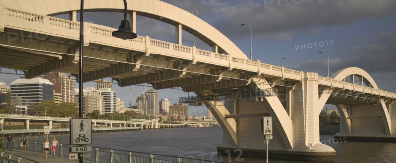AUSTRALIA, Queensland, Brisbane, Walkers strolling along the River Walk beneath a road bridge over the Brisbane River.