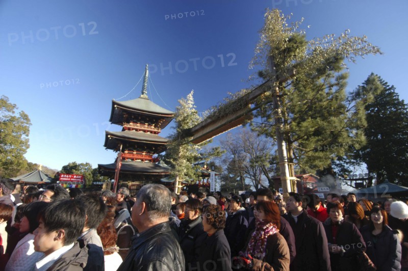 JAPAN, Honshu, Chiba , "Narita San Temple. New Years Holiday worshippers crowd the front court of the temple with the pagoda and traditional gate of pine, bamboo and bundled rice straw behind "