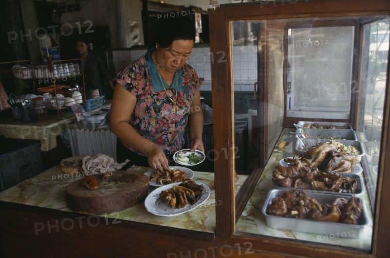 LAOS, Food, Cooking, Woman preparing dish of cooked meats in restaurant.