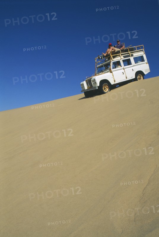 NAMIBIA, Skeleton Coast, Terrace Bay, Dune driving on the Roaring Dunes with jeep on crest of dune.