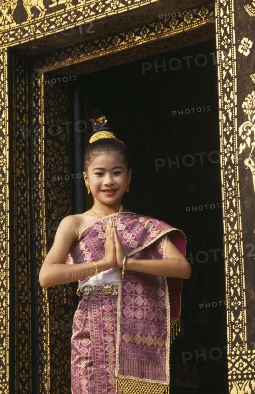 LAOS, Luang Prabang, Young girl dressed for New Year festivities framed in doorway of temple.