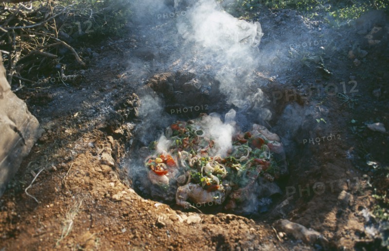 LIBYA, Cyranaica, Cooking meat on hot stones in a hole in the ground.