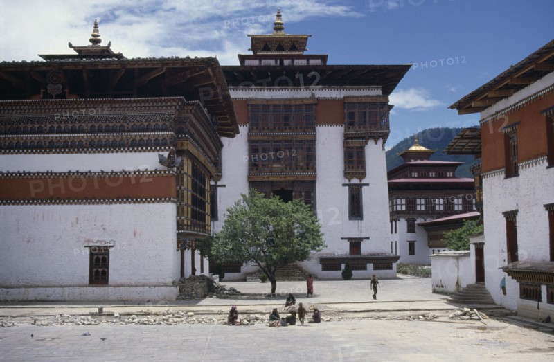 BHUTAN, Thimpu, Tashicho Dzong courtyard with traditional architecture and small group of women and children in middle foreground.