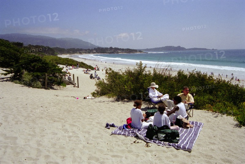 USA, California, Carmel, Carmel Beach with people on blanket among sand dunes in the foreground