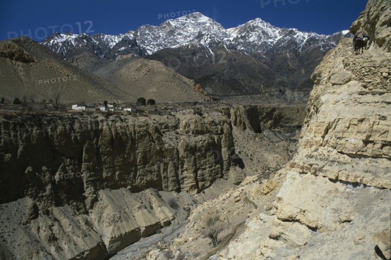 NEPAL, Mustang, Mountain pass and steep sided gorge with snow capped mountain peaks in the distance.