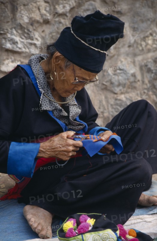 LAOS, Luang Prabang, Hmong woman embroidering traditional textile.
