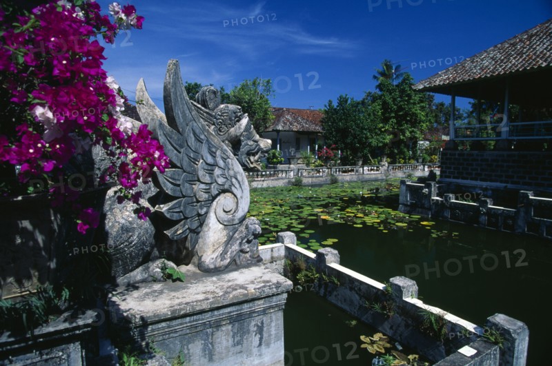 INDONESIA, Bali, Amlapura, Ornamental lake with water lillies at the old palace of the Raja of Karangasem.  Winged dragon statue in foreground.