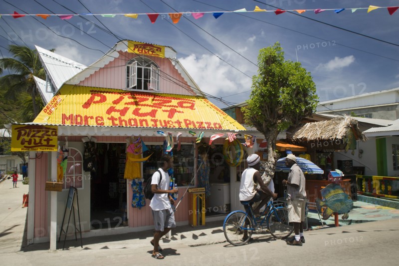WEST INDIES, St Vincent & The Grenadines, Union Island, Men talking outside pizza restaurant and tourist shop in Clifton