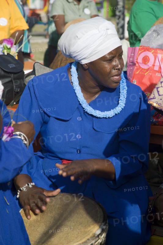 WEST INDIES, St Vincent & The Grenadines, Union Island, Woman playing a drum amongst the Baptist congregation in Clifton at Easter morning harbourside service for those lost at sea