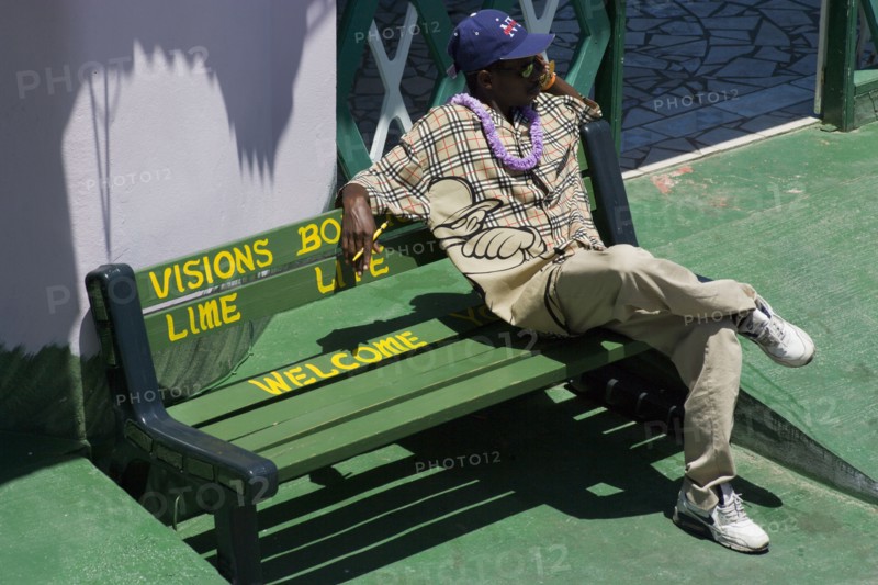 WEST INDIES, St Vincent & The Grenadines, Union Island, Man sitting on pavement bench in Clifton
