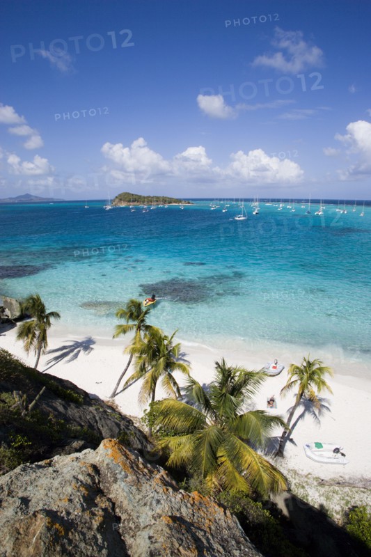 WEST INDIES, St Vincent & The Grenadines, Tobago Cays, View over the beach of Jamesby Island and moored yachts towards Canouan on the horizon