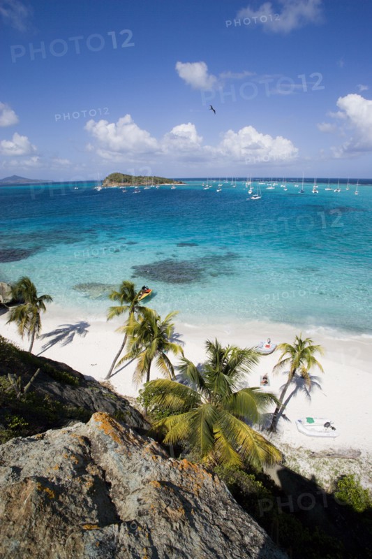 WEST INDIES, St Vincent & The Grenadines, Tobago Cays, View over the beach of Jamesby Island and moored yachts towards Canouan on the horizon