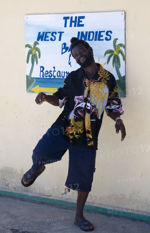 WEST INDIES, St Vincent & The Grenadines, Union Island, Man dancing beside a restaurant sign in Clifton