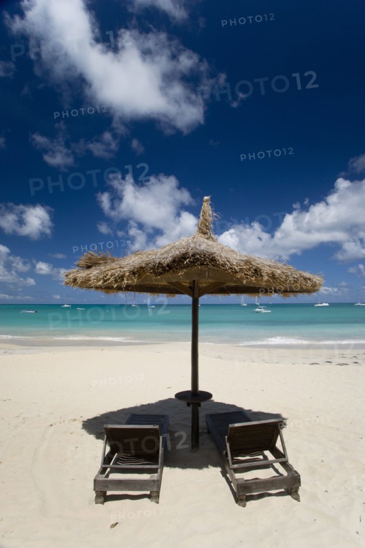 WEST INDIES, St Vincent & The Grenadines, Canouan, Palapa thatched shelter and sunbeds at Tamarind Beach Hotel in Charles Bay with moored yachts