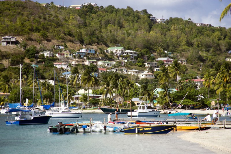 WEST INDIES, St Vincent & The Grenadines, Bequia, Jetty with moored yachts in Admiralty Bay with hillside houses beyond in Port Elizabeth