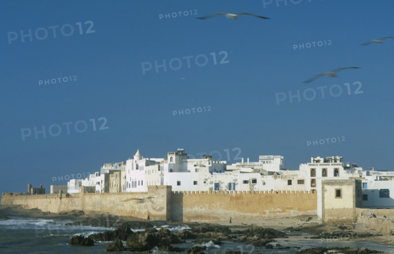 MOROCCO, Essaouira, Fortified coastal town with waves breaking against rocks in the foreground.
