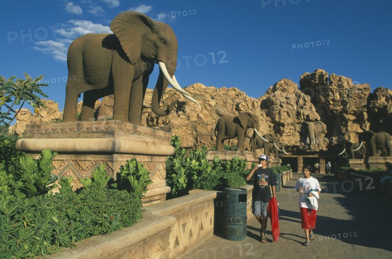 SOUTH AFRICA, North West, Sun City, Tourist visitors on avenue lined with statues of elephants.
