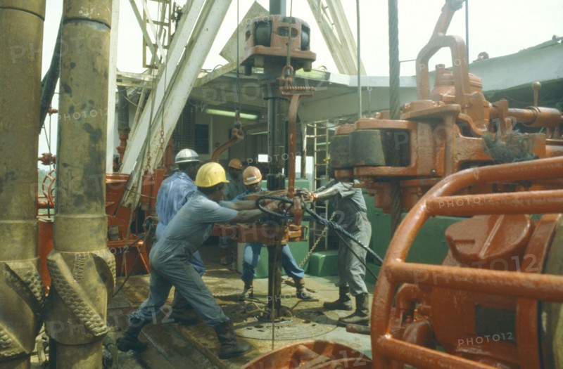 NIGERIA, Rivers State, Workers using drill on oil rig.