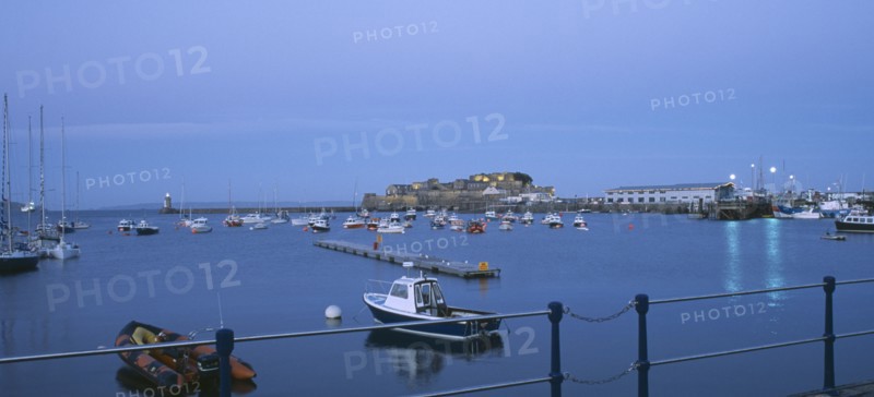UNITED KINGDOM, Channel Islands, Guernsey, St Peter Port. Cornet Castle at dusk seen from across water.
