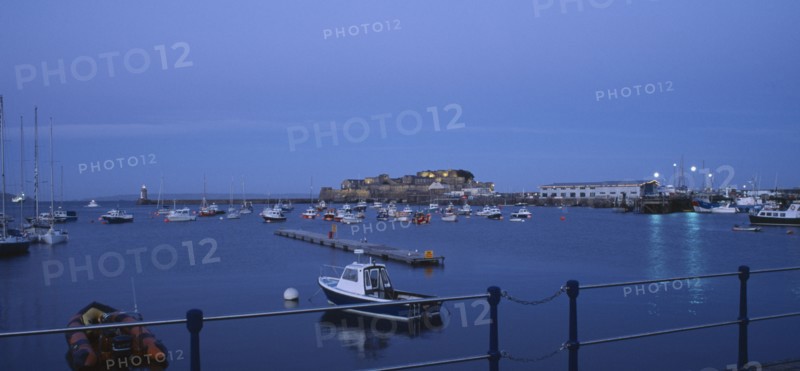 UNITED KINGDOM, Channel Islands, Guernsey, St Peter Port. Cornet Castle at dusk seen from across water.