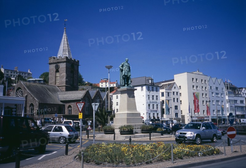 UNITED KINGDOM, Channel Islands, Guernsey, "St Peter Port. Albert Prince Consort statue on weighbridge roundabout with the town church behind. The Albion House pub, restaurants, and shops lining the esplanade"