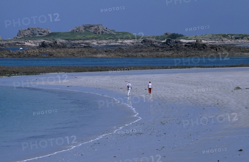 UNITED KINGDOM, Channel Islands, Guernsey, Castel. Cobo Bay. View across sandy shoreline with people walking on sand.