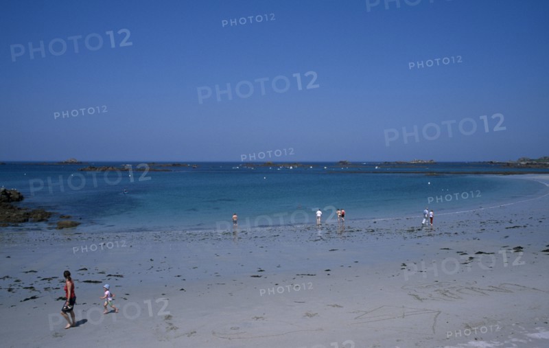 UNITED KINGDOM, Channel Islands, Guernsey, Castel. Cobo Bay. View across beach towards sea with people paddling and walking along the sand