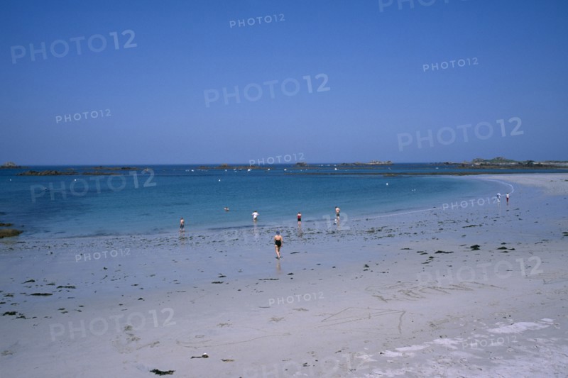 UNITED KINGDOM, Channel Islands, Guernsey, Castel. Cobo Bay. Sandy beach with people paddling at the waters edge