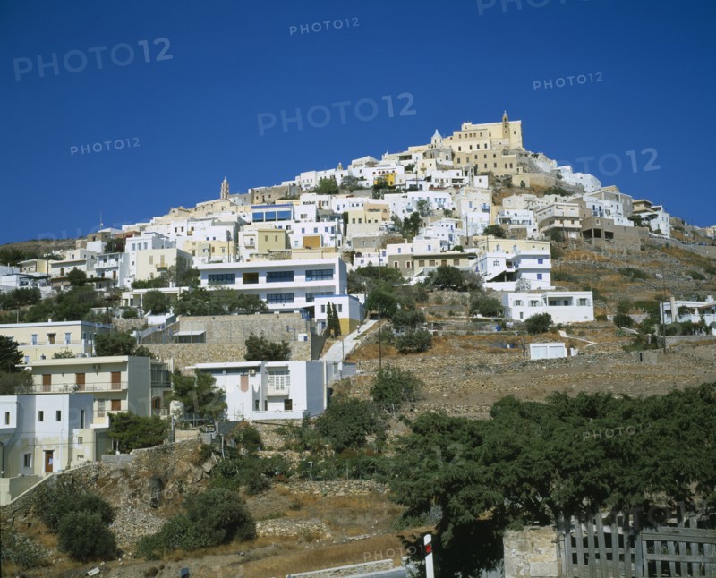 GREECE, Cyclades Islands, Syros, Ermoupolis. The Catholic quater of Ano Syros and church of Ag. Yiorgios. Houses covering mountain side with trees and a wall in the foreground.
