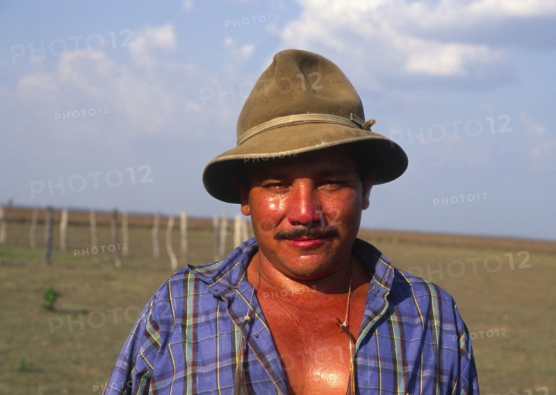 COLOMBIA, Casanare, Llanero cowboy wearing a hat and standing in a field.