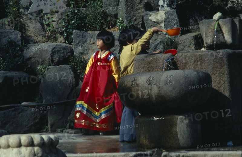 SOUTH KOREA, Children, Children wearing traditional dress drinking from well.