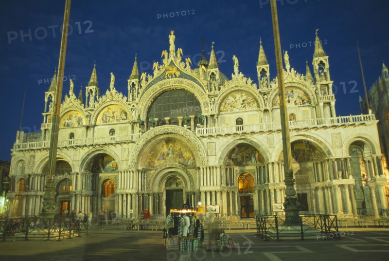 ITALY, Veneto, Venice, Basilica di San Marco exterior facade at night with clothing stall in square in the foreground