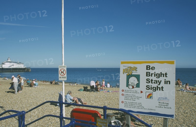 ENGLAND, East Sussex, Eastbourne, Child safety awarness sign Kid Zone displayed next to railings on busy beach.