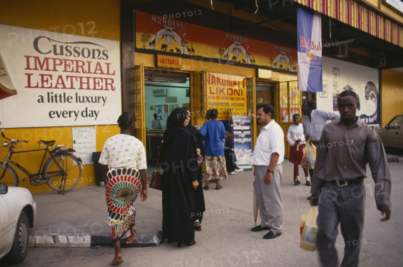 KENYA, Mombasa, Street scene with people outside superstore with brightly coloured facade and advertising.