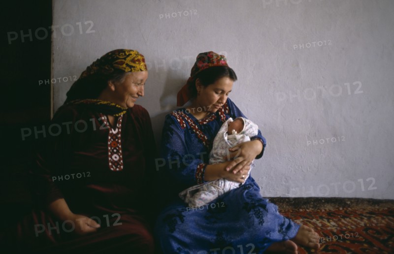 TURKMENISTAN, Ashkhabad, Women in traditional dress with baby at home.